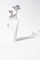 Moisturizer hand cream white plastic tube mockup on white trandy background with flower and hard shadows. Blank skin care beauty product packaging photo