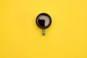 Cup of black coffe on yellow background. Creative concept of hot drinks. Top vie, copy space photo