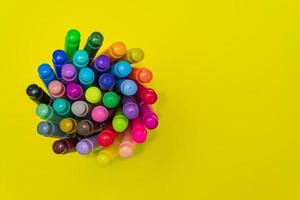 Set of felt tip pens rolled on a bright yellow background. Top view. Art and school creative concept with copy space photo