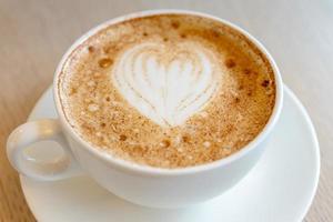 Cup of freshly brewed Cappuccino with latte art foam on a table of the cafeteria photo