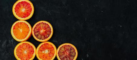 Organic Raw Red Blood Oranges in a rows on a black background. Copy space for text. Banner photo