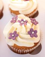 Closeup photo of colorful cupcakes with sugar icing in paper box