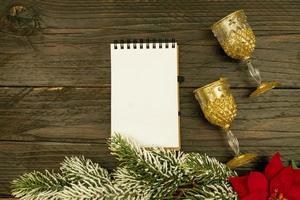 Happy New year 2021 celebration. Champagne glasses and blanck spyral notepad on wooden background. Flat lay. photo