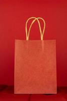 Single red shopping paper bag on red background. Black friday monochromatic concept. Mock up. photo