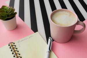 Self isolation concept. Open notepad with quarantine plan during coronavirus pandemia. Pink cup of capuccino on a table photo