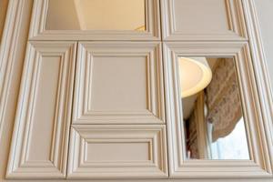 Classical interior of a living room with molding frames and mirrors. Pastel beige appartment design photo