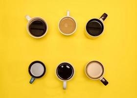 Lots of coffe cups wth different cups of coffee on yellow background. Trendy concept, top view photo