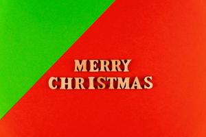 wooden letters on red background. Merry christmas lettering in red paper. Copy space photo