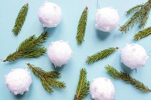 Christmas minimal concept - Christmas composition with fir branches and white baubles. Horizontal frame, flat lay, view from above. Pastel blue background with copy space photo