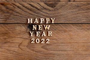 feliz año nuevo 2022. cita hecha con letras de madera y números 2022 sobre fondo de madera. concepto creativo para la tarjeta de felicitación de año nuevo foto