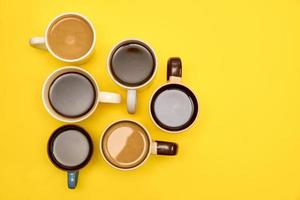 muchas tazas de café caliente aromático diferente sobre fondo amarillo, vista superior, espacio de copia foto