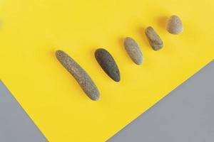 Flat lay in a trendy 2021 new colors. Illuminating Yellow and Ultimate Gray. Color of the Year 2021. Grey sea stones on yellow background. photo