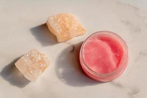 Himalayan salt and pink body or face scrub on marble background. Bath salt. Spa treatment. beauty and relaxation concept. photo