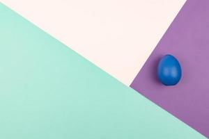 Abstract geometric paper background of pastel pink and purple colors with blue easter egg. Copy space for design photo