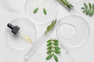 Laboratory glassware with serum and oil on white background. Natural medicine, cosmetic research, bio science, organic skin care products with herbal extracts. Flat lay, top view photo