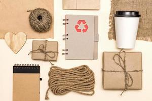 products made from recycled kraft paperand wood - packages, notebook, disposable coffee cup, wooden heart, cord. concept of environmental protection, recycling business. top view photo