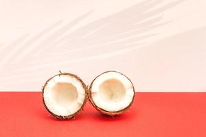 Two halves of fresh raw coconut on red backgound with kight shadows in white. photo