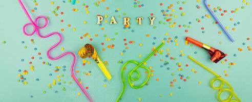 Bright festive party background - cocktail straws and party whistles on blue background with scattered sugar sprinkles. photo