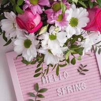 Pink letterboard with quote Hellow Spring and blooming tender bouquet of flowers. Top view. Festive greeting card photo