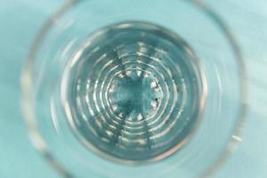 Top view of glass with water on blue background. Abstract backdrop photo