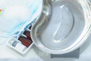 Kidney-shaped tray, set of ampoules and medicine mask on a table. Beauty procedures cabinet photo