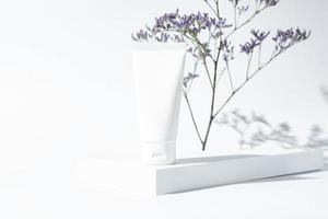 beauty spa medical skincare concept with cosmetic lotion or cream bottle packaging tube on white background with dried flower branch on a podium. photo