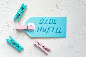 Handwriting text Side Hustle on a blue tag. Concept of extra cash. Colored clothespin around. photo