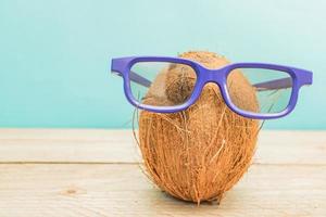 A cocnut wearing 3D glasses on blue background. Summer and trave concept photo