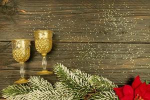 Happy New year 2021 celebration.Champagne glasses and poinsettia on wooden background. Flat lay. photo