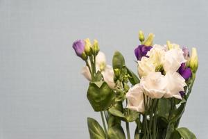 Bouquet of white and violet Eustoma flowers on grey background. Spring flowers. photo