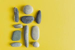 Flat lay in a trendy 2021 new colors. Illuminating Yellow and Ultimate Gray. Color of the Year 2021. Grey sea stones on yellow background. photo