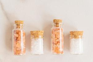 Set of glass bottles with pink himalayan and white sea salt on marble background. photo