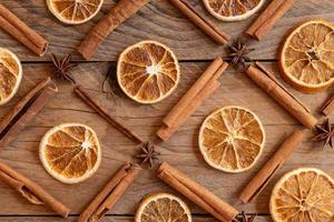 Cinnamon sticks, slices of dried orange, star anise on wooden background. Top view. Christmas and New Year celebration concept. Pattern backdrop photo