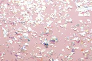 confeti de lámina de perla de neón sobre fondo rosa claro. telón de fondo festivo, fiesta o vacaciones. endecha plana, vista superior. foto