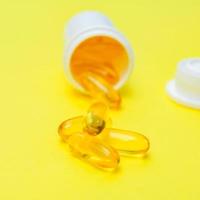 omega 3 fish oil gel capsules on yellow background. Creative health care concept photo