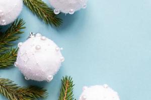 Christmas minimal concept - Christmas composition with fir branches and white baubles. Horizontal frame, flat lay, view from above. Pastel blue background with copy space photo