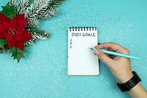 Female hand writing 2021 goals for new year. Resolutions list. photo