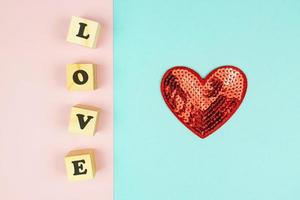 corazones rojos y cubos de madera con texto amor sobre doble fondo azul y rosa. piso creativo con espacio de copia. tarjeta de felicitación festiva para el día de san valentín. foto