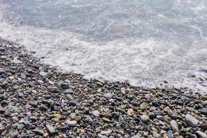 costa de guijarros. orilla del mar con agua transparente y pequeñas piedras foto