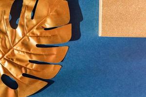 Fashionable luxuary blue background with gold monstera leaf. Copy space for text photo