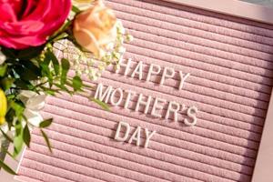 feliz fondo del día de la madre con tablero de letras rosa y flores de primavera. foto