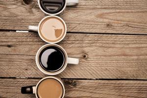 Many cups with tasty aromatic coffee on wooden table. Top view with copy space photo