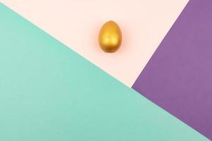 Abstract geometric paper background of pastel pink and purple colors with golden easter egg. Copy space for design photo