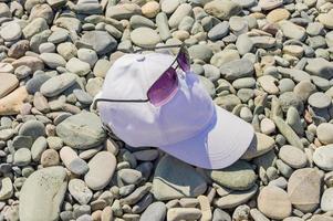 Baseball caps and sunglasses lie on a gravel photo