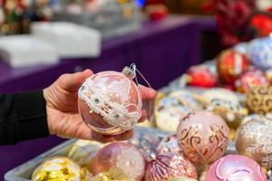 Female hand holding in the store a toy bauble, Christmas decoration. Preparation for the holidays photo