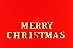 wooden letters on red background. Merry christmas lettering in red paper. Copy space photo