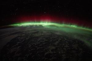 An aurora crowns the Earth beneath a starry sky photo