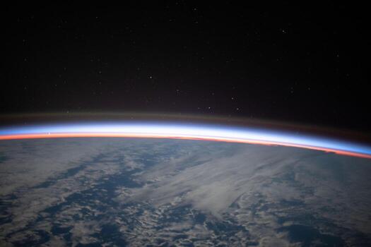 The first rays of an orbital sunrise begin illuminating Earth's atmosphere in this photograph from the International Space Station photo