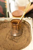 Turkish coffee prepared on hot sand for an unique taste and aroma. Traditional oriental beverage in copper cezve photo