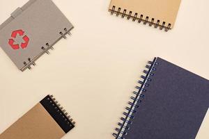 top view eco friendly notebooks for office, with copy space made of recycled paper on a pastel background. recycle mark on the cover photo